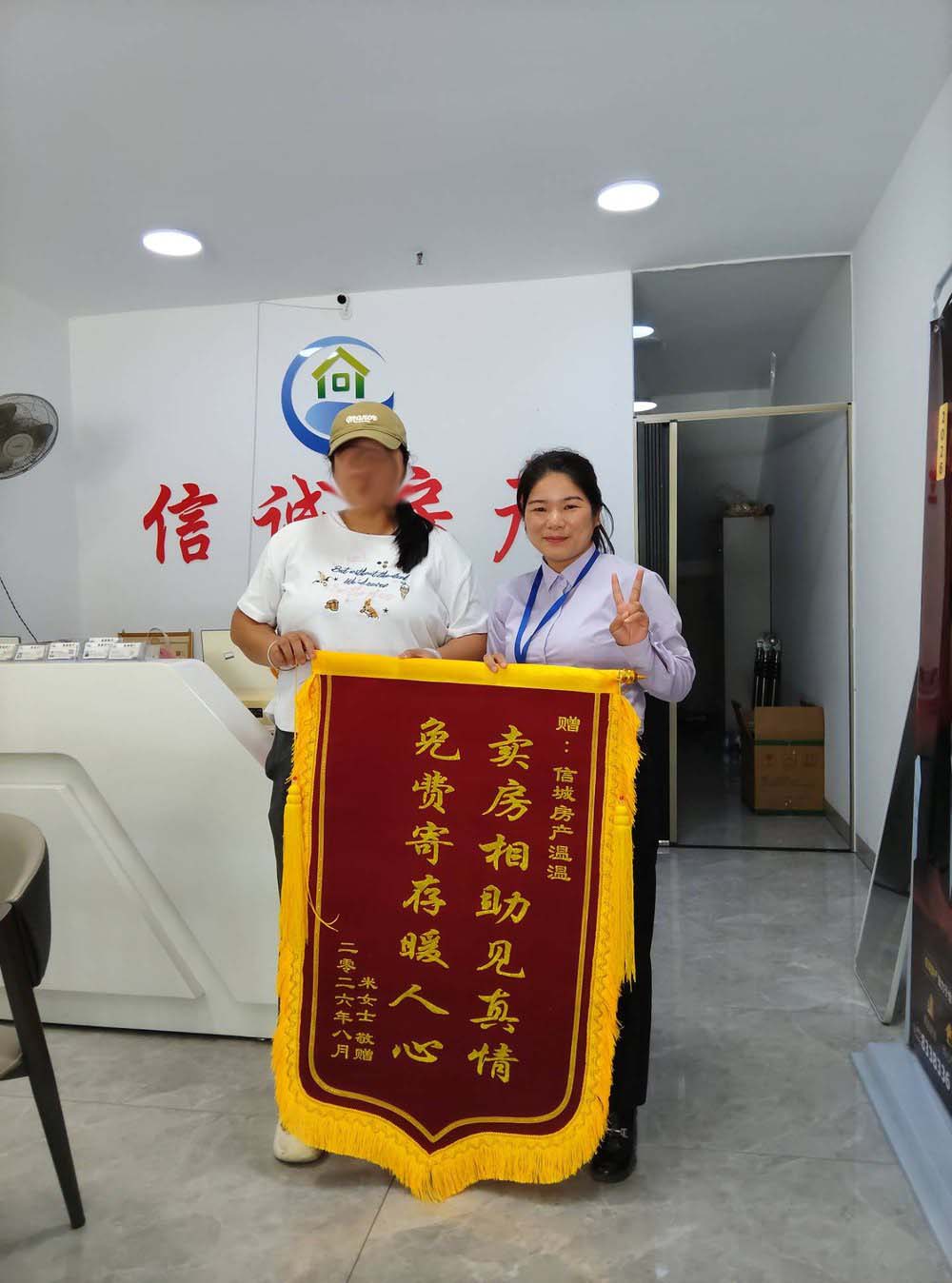 2026 年 8 月，买方米女士向浦北县信诚房地产中介有限公司（浦北信诚房产）经纪人温温赠送锦旗的门店合影，锦旗上书「卖房相助见真情 免费寄存暖人心」